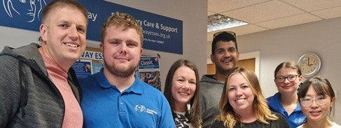 Seven individuals grouped and smiling at the camera, at Headway centre in Colchester