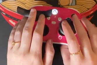 Close-up of hands with gold rings on a red and yellow object.