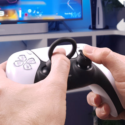 Close-up of hands holding a gaming controller with Thumb Soldiers Racer attachments in front of a blurred background
