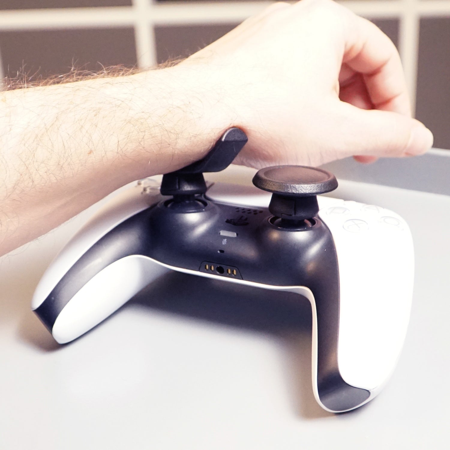 Person using a gaming controller with Thumb Soldiers Rest kit on a white background