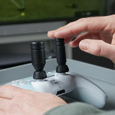 Close-up of a person using Thumb Soldiers Sticks kit on a gaming controller in front of a blurred background